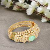 Luxurious gold bracelet with emerald and diamond accents exudes timeless sophistication and regal charm.
